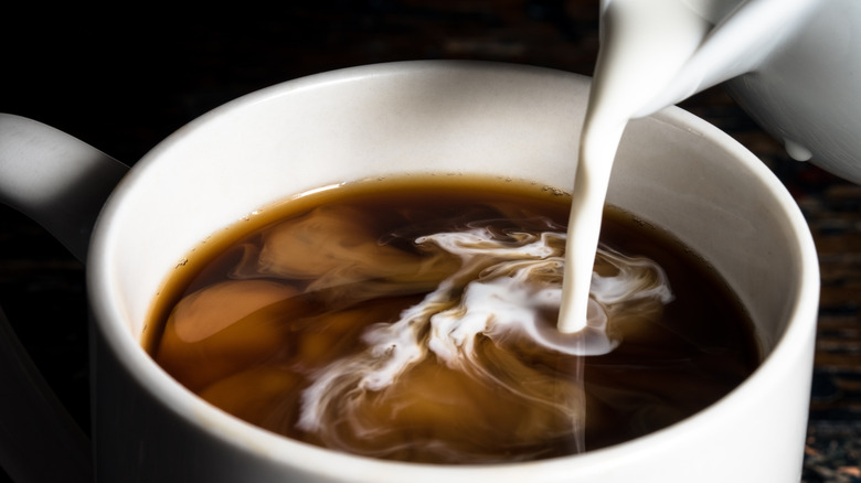 Coffee creamer poured into cup of coffee