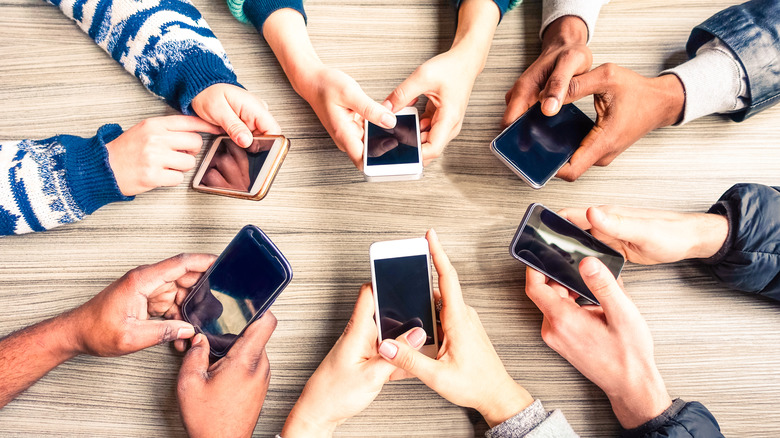 Circle of hands holding their phones