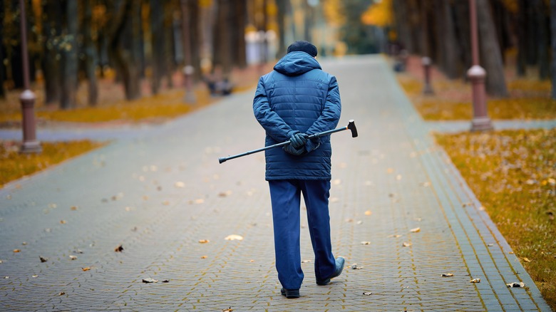 elderly man casually walking away holding his cane