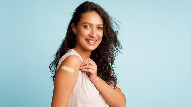 Smiling woman showing bandage from COVID-19 vaccine