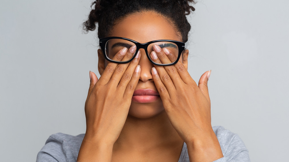 Woman with glasses rubbing her eyes