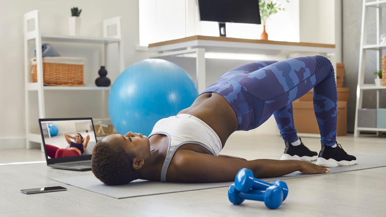 woman doing yoga next to laptop