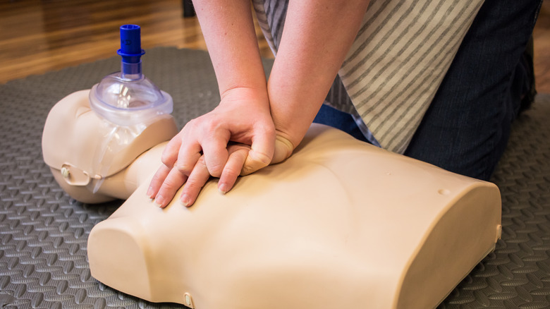 Someone practicing CPR on a dummy