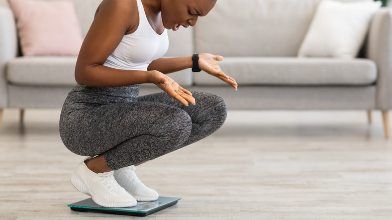 Woman looking at scale with disgust