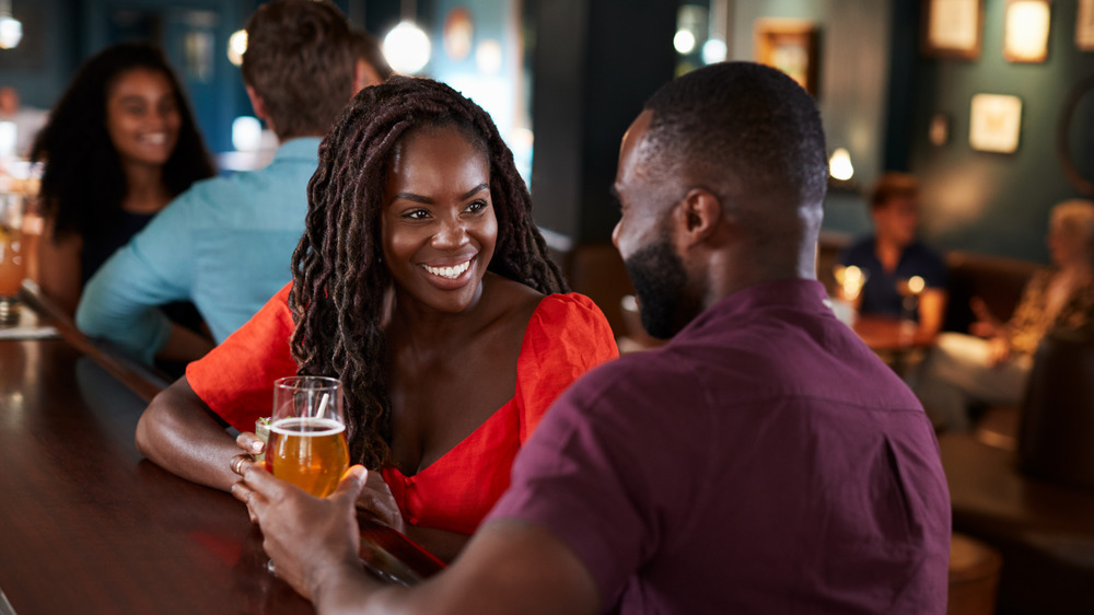 Young black couple sitting at a bar smiling