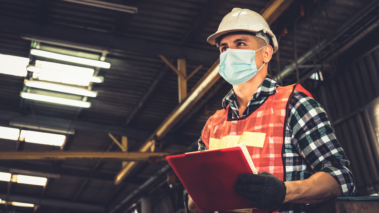 Factory worker wearing a reflective vest and facemask 