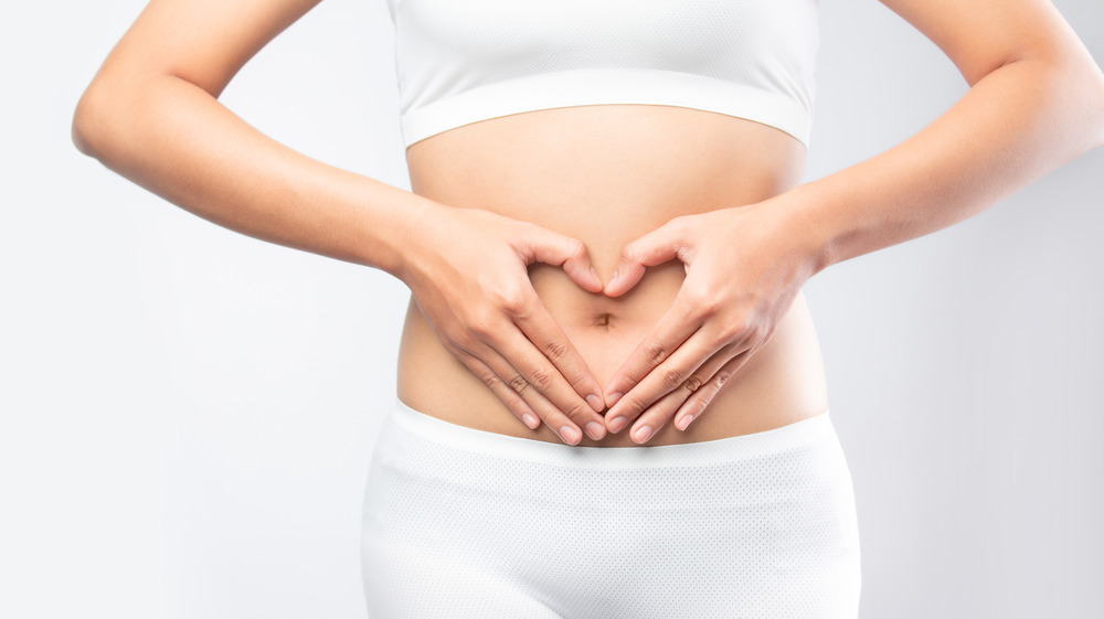 Closeup of a woman making a heart with her hands over her tummy