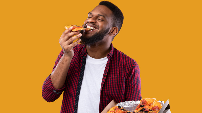 a man smiling and eating pizza