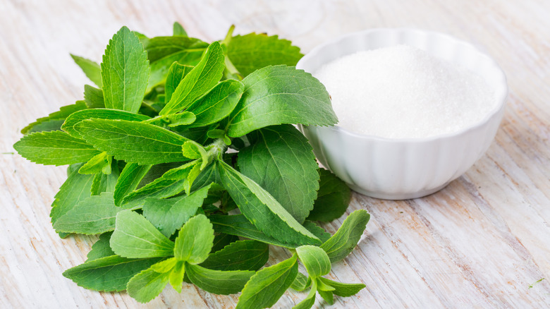 Stevia leaves next to bowl of stevia powder