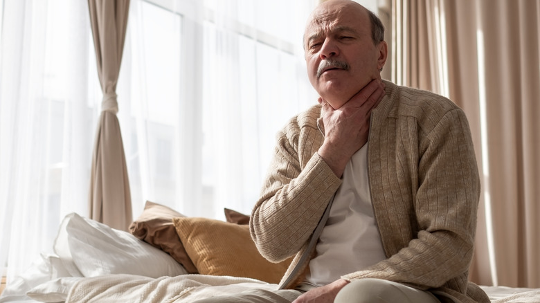 Elderly man holding his neck