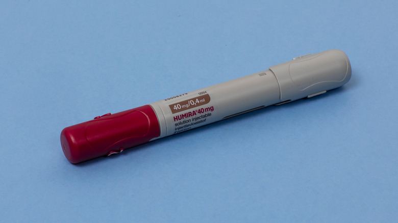 Humira auto-injector on blue surface