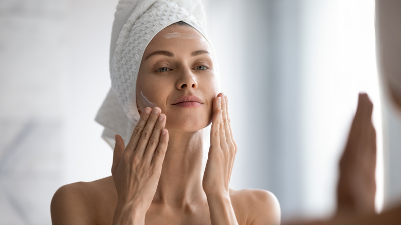 Woman applying lotion to her face