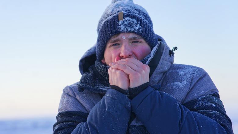 A man shivers and tries to warm his hands