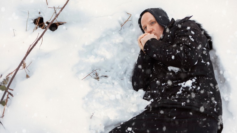 a man lies shivering in the snow