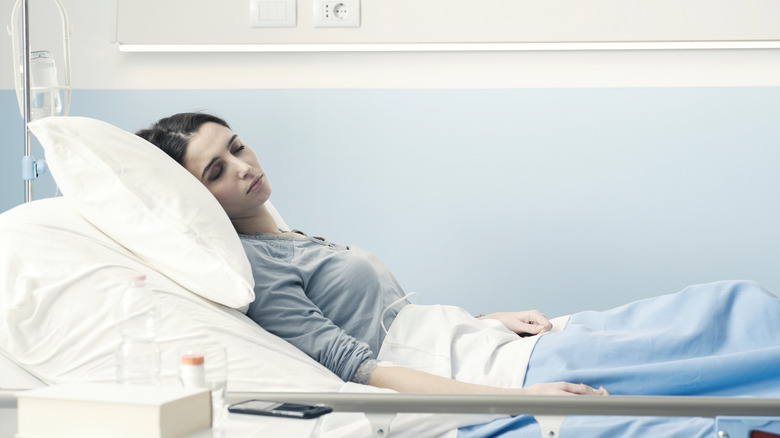 a woman recovers in a hospital bed with an IV