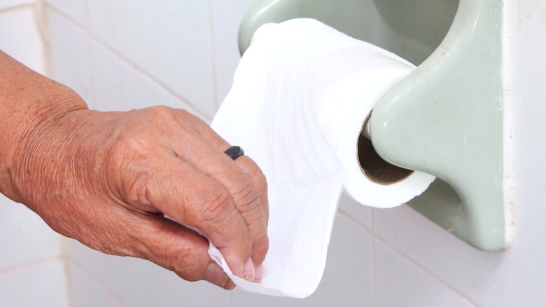elderly woman pulling toilet paper