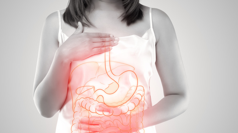 Woman holding her stomach with an overlay of the internal organs