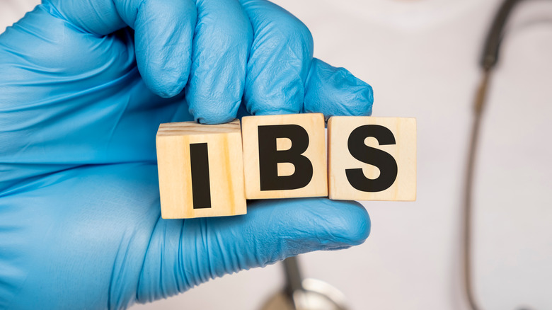 Gloved hand holding blocks that says "IBS."