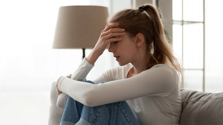 A woman sitting with her knees bent up and her face in her hand