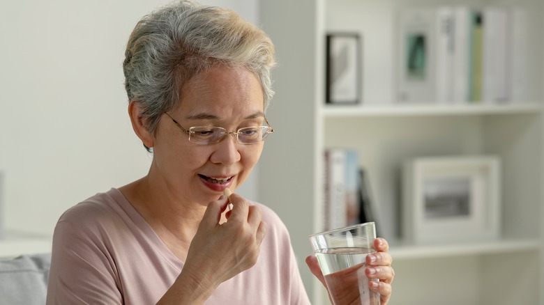 Senior woman smiling and taking medication