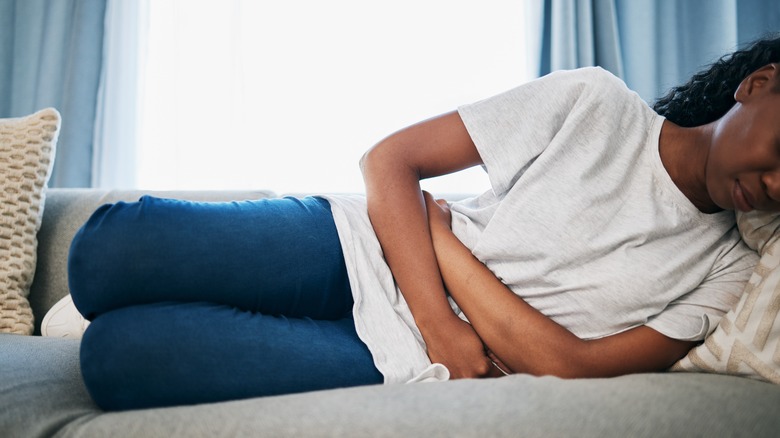 Woman in pain laying down on couch 