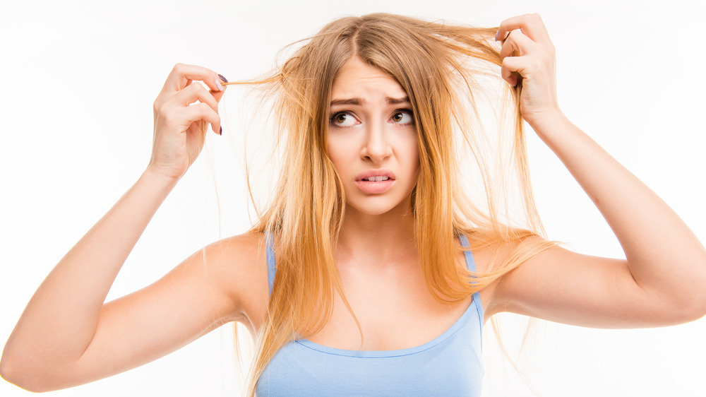 Woman holding her hair out in both hands looking distressed.