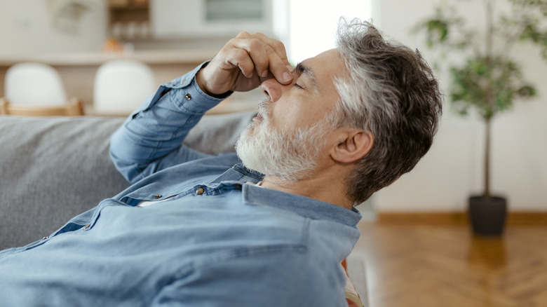 Man laying on couch with headache