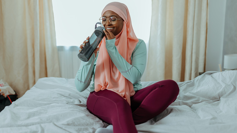 Smiling woman drinking out of water bottle