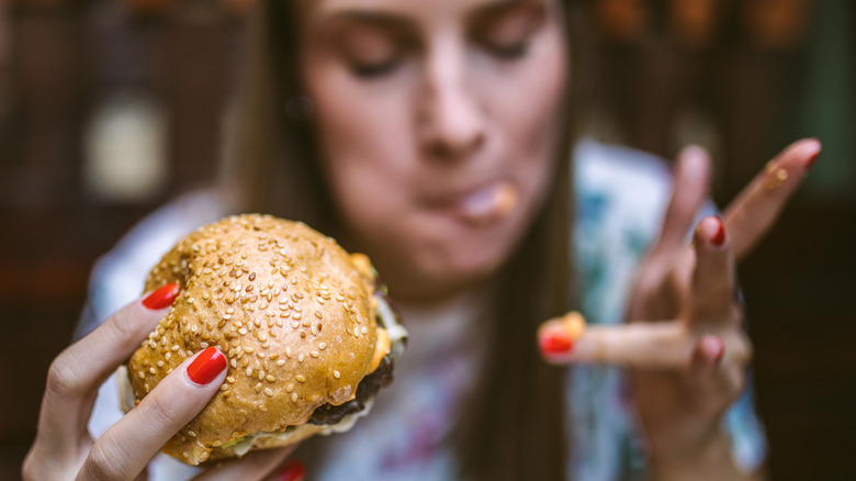 woman eating hamburger with hands