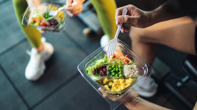 people holding healthy meals at gym