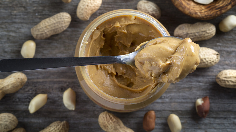 spoonful of peanut butter over a peanut butter jar