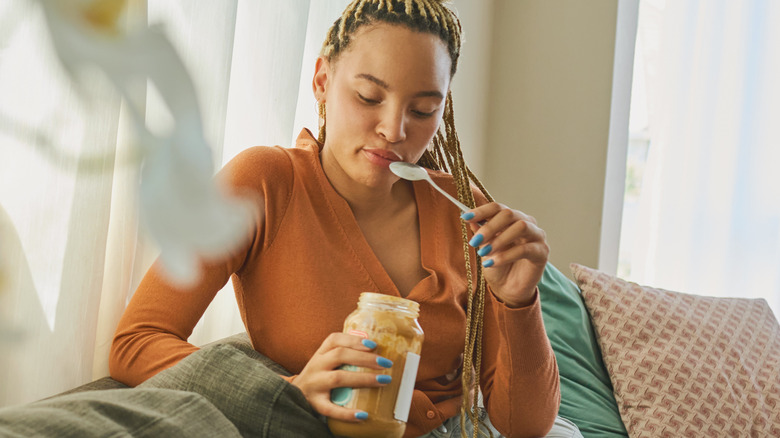 woman eating peanut butter from a jar