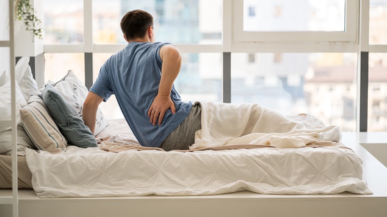 a man with back pain getting out of bed