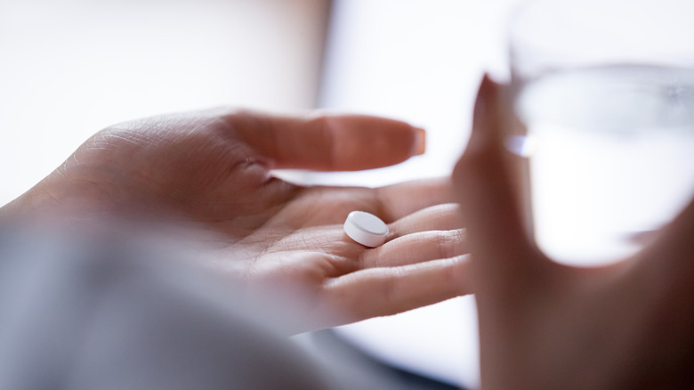 Close up of a woman's hand holding a pill