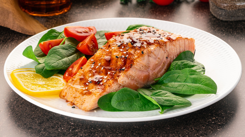 A plate of glazed salmon with spinach and tomato