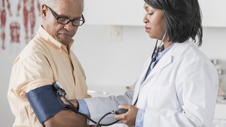 A medical provider screening a man for high blood pressure