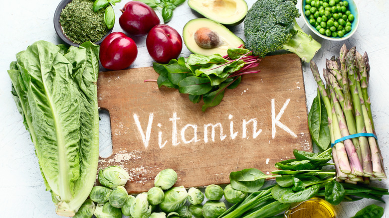 Top view of foods rich in vitamin K, cutting board in middle with "vitamin K" written on it