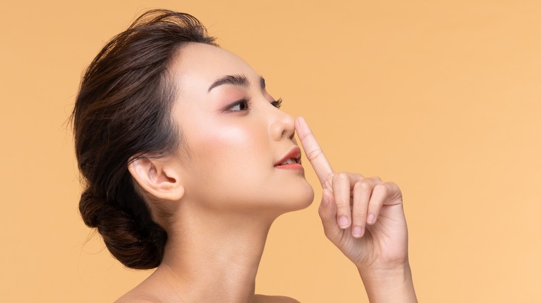 Asian woman pointing to her nose