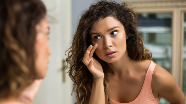Woman examining her eye in mirror