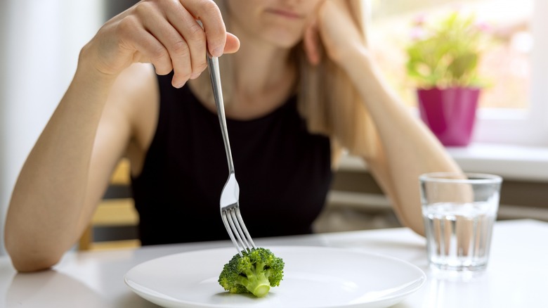 woman on fad diet eats broccoli