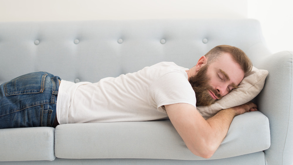 Man sleeping on stomach on couch