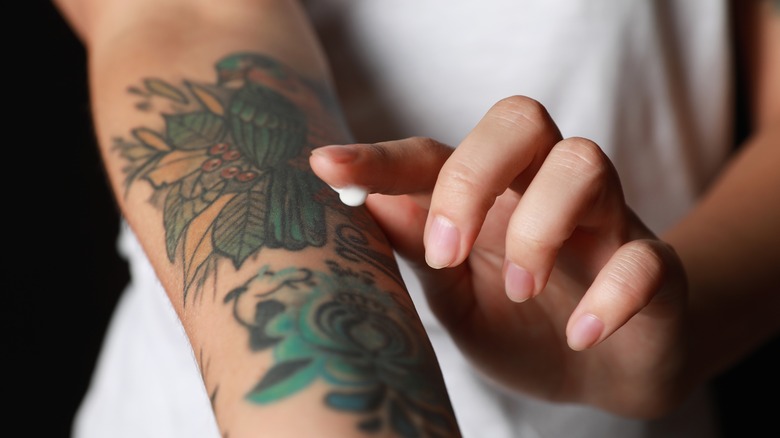 Woman applying lotion to tattoo 