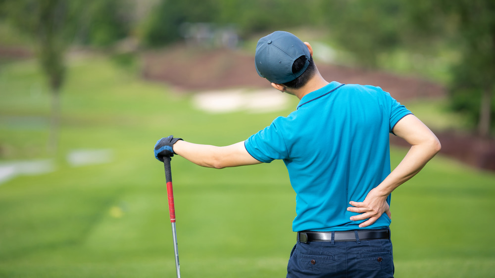man holding back playing golf