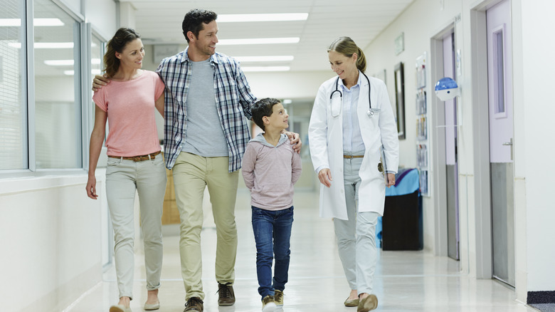 family and doctor walking in hall of medical center