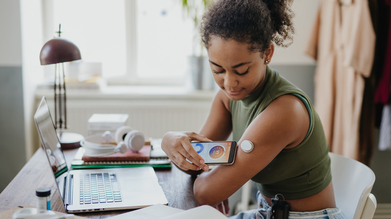 woman measuring her blood sugar using smartphone