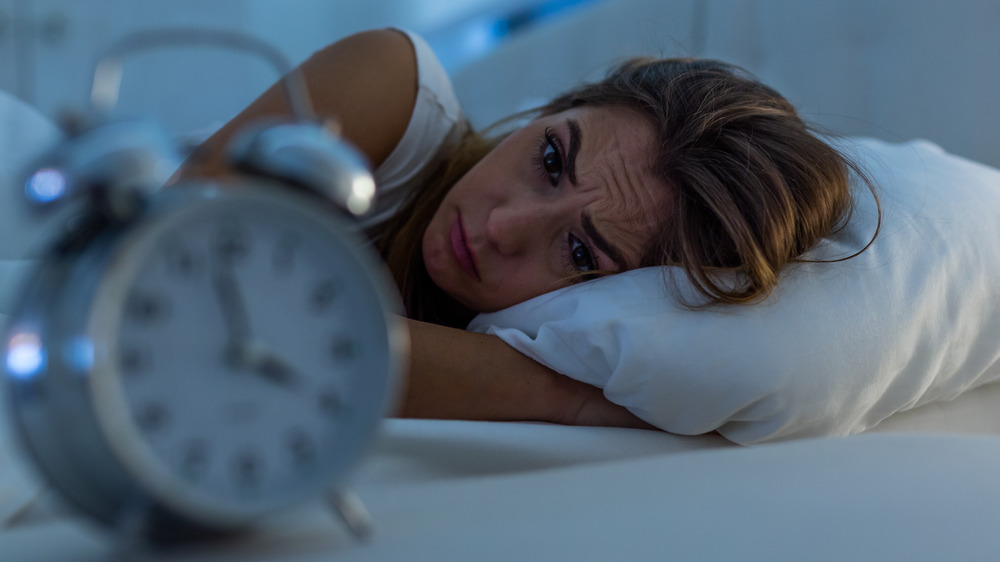 alarm clock, woman lying in bed with eyes open