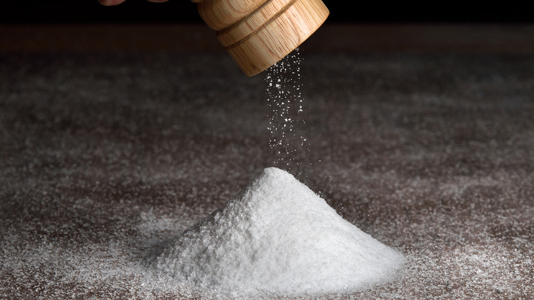 A pile of salt beneath a salt grinder