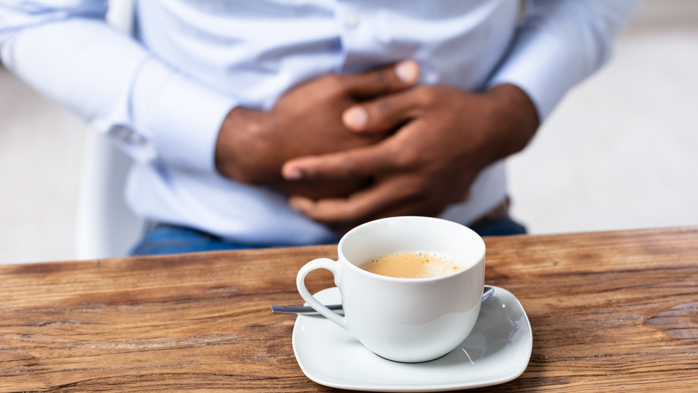 coffee cup, man holding stomach 