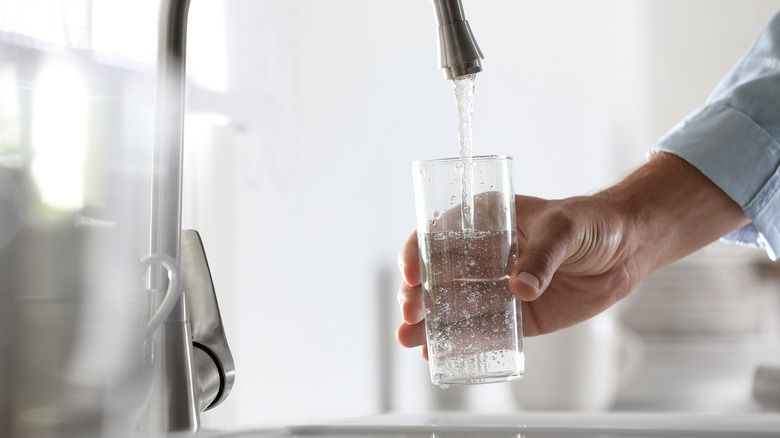 man gets drinking water from fountain