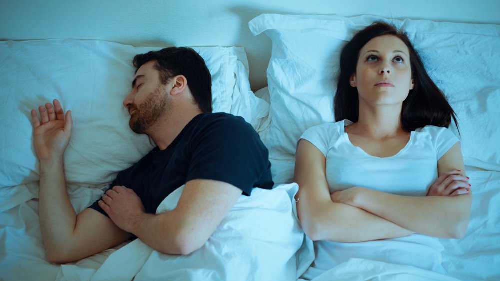 man snoring and woman awake in bed